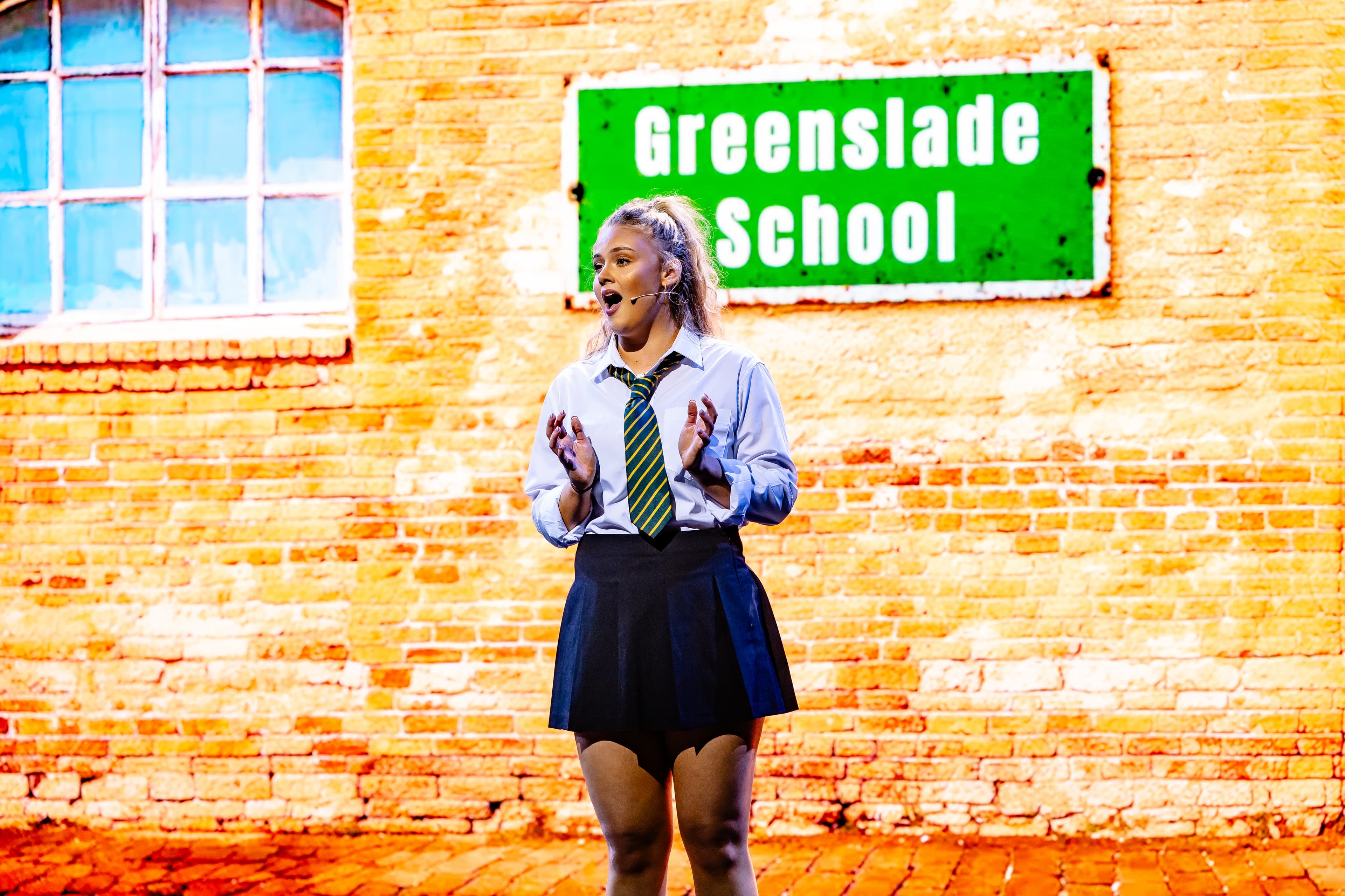 Young performer from To Sir, With Love in school uniform on stage